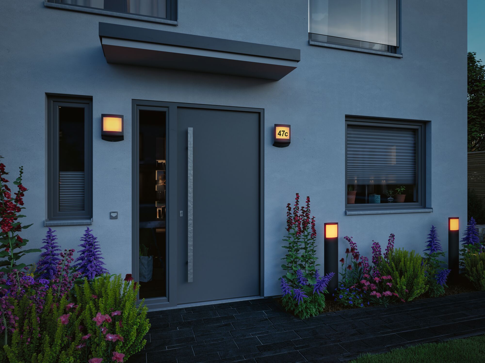 Moderne buitenverlichting met warm wit licht aan gevel en tuinpad met planten.