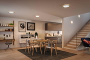 Modern dining room with wooden chairs, table and round ceiling lights emitting warm white light