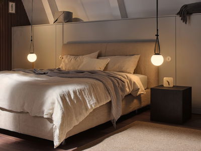 Cozy bedroom with beige fabric bed and two warm white pendant lights for ambient lighting