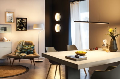 Modern living room with white floor lamp, round wall lights, and black pendant light above dining table