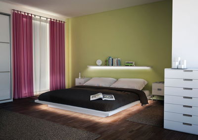 Modernes Schlafzimmer mit beleuchtetem weißen Bett, grünem Wandregal und pinken Vorhängen für gemütliche Atmosphäre
