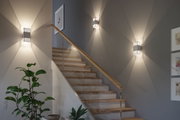 Moderne weiße Wandleuchte aus Metall mit dekorativem Lichtmuster an Treppenhauswand