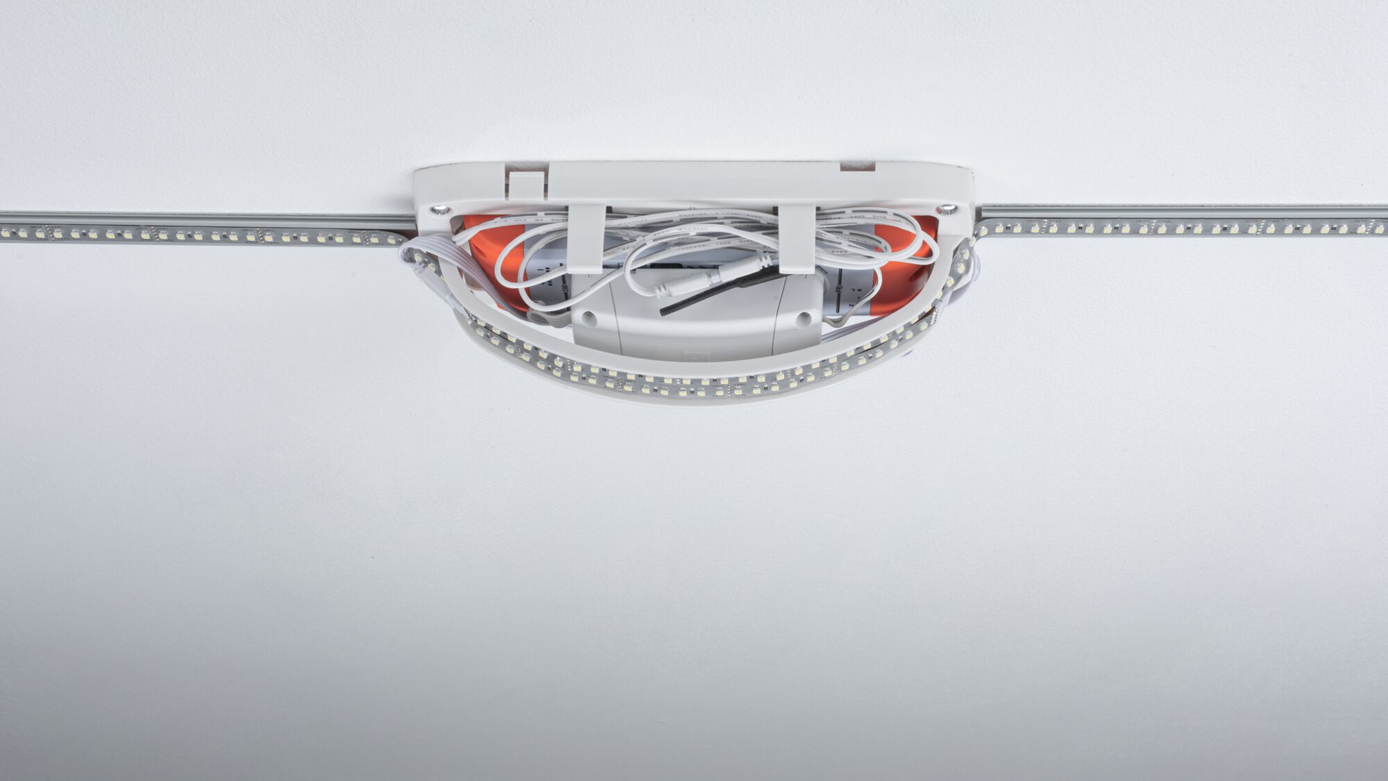 Weiße LED-Lichtleiste mit Kabeln und Anschlussbox an der Decke montiert für moderne Raumbeleuchtung