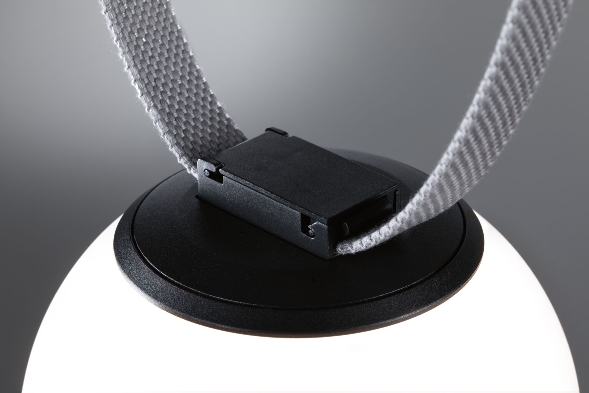 Close-up of black plastic clasp with grey fabric strap on LED lighting fixture for modern interiors