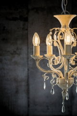 Antique white metal chandelier with decorative crystal drops and warm LED light for living spaces