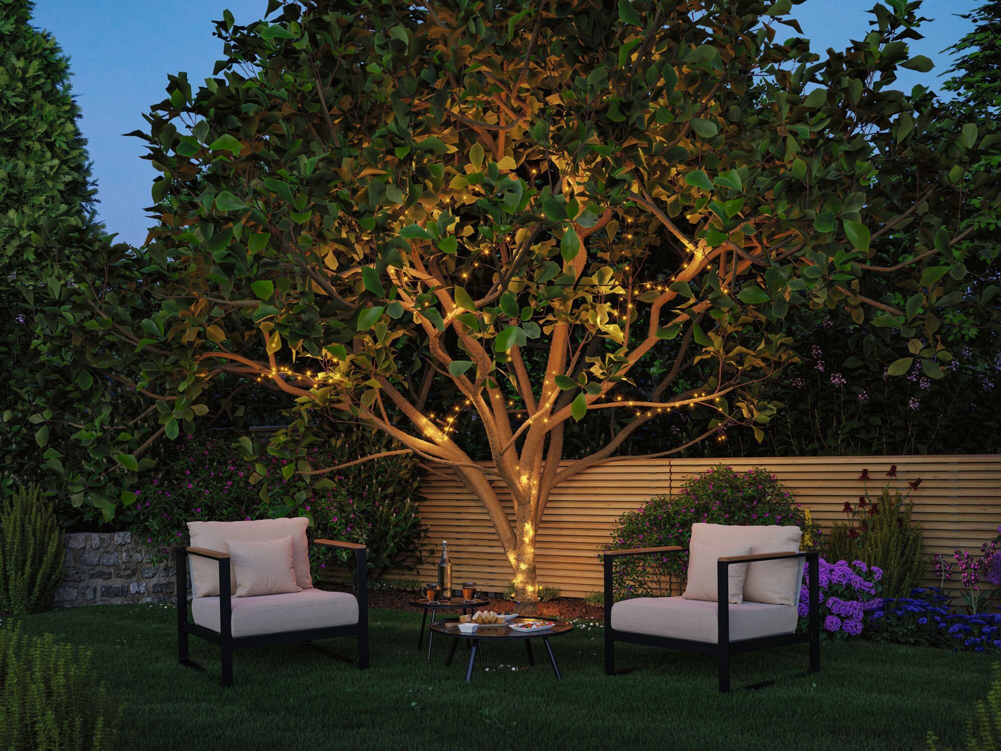 Garten mit Baum, der mit warmweißen LED-Lichterketten umwickelt ist, gemütliche Sitzmöbel und Pflanzen