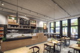 Modern café met houten balie, zwarte hanglampen en grote ramen voor een gezellige sfeer