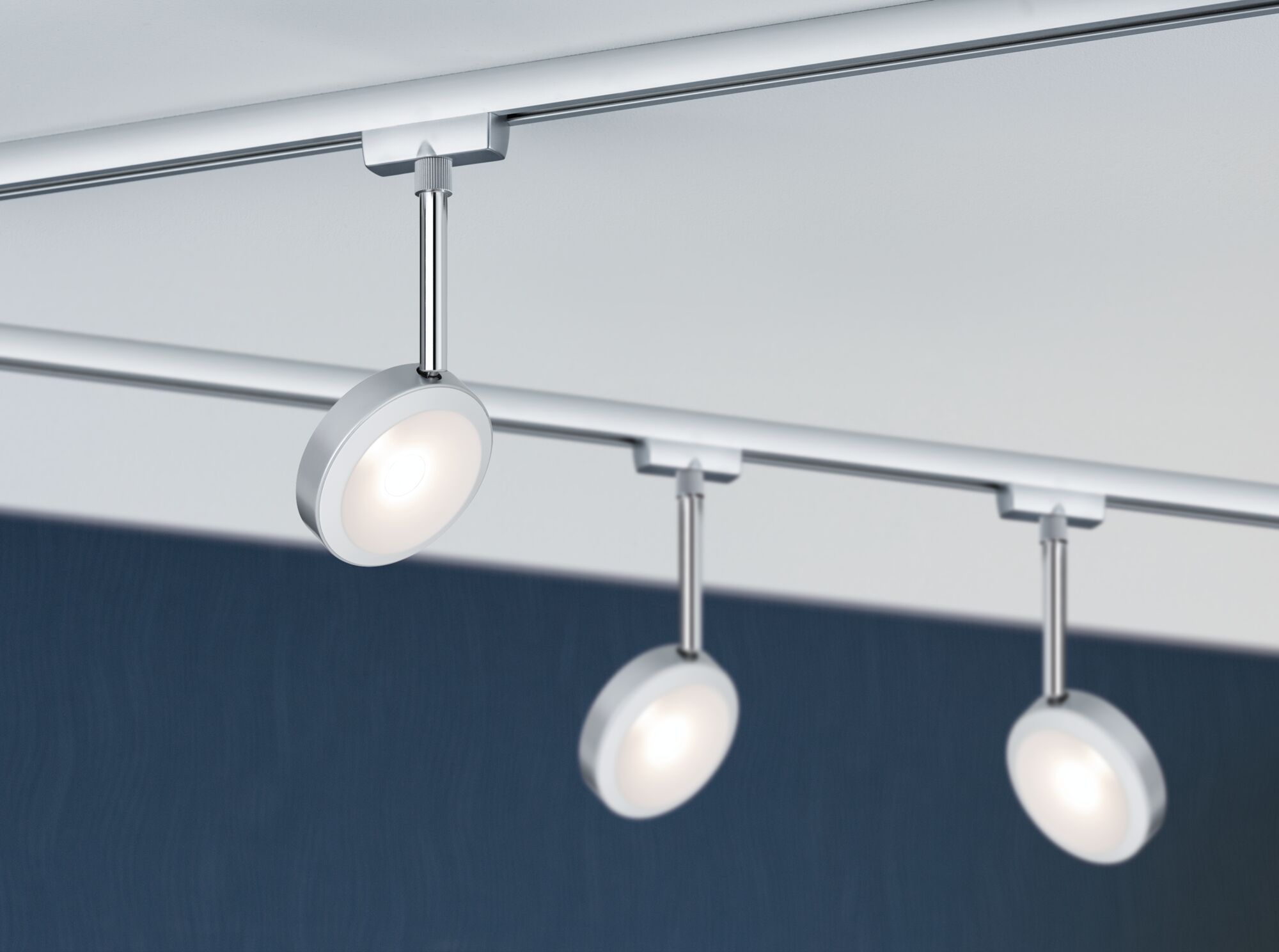 Three round silver LED spotlights on track system for modern room lighting