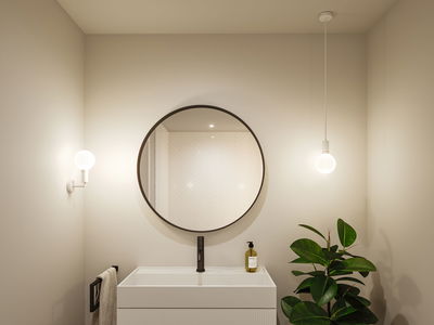 Modern bathroom with round mirror, white sink, and two white lights providing ambient lighting