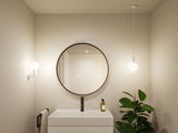 Modern bathroom with round mirror, white sink, and two white lights providing ambient lighting