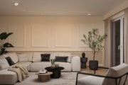 Modern living room with beige corner sofa, black and wooden coffee tables, plants, and ceiling spotlights
