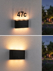 Black solar wall light with warm white LED and house number 47c on exterior wall at dusk