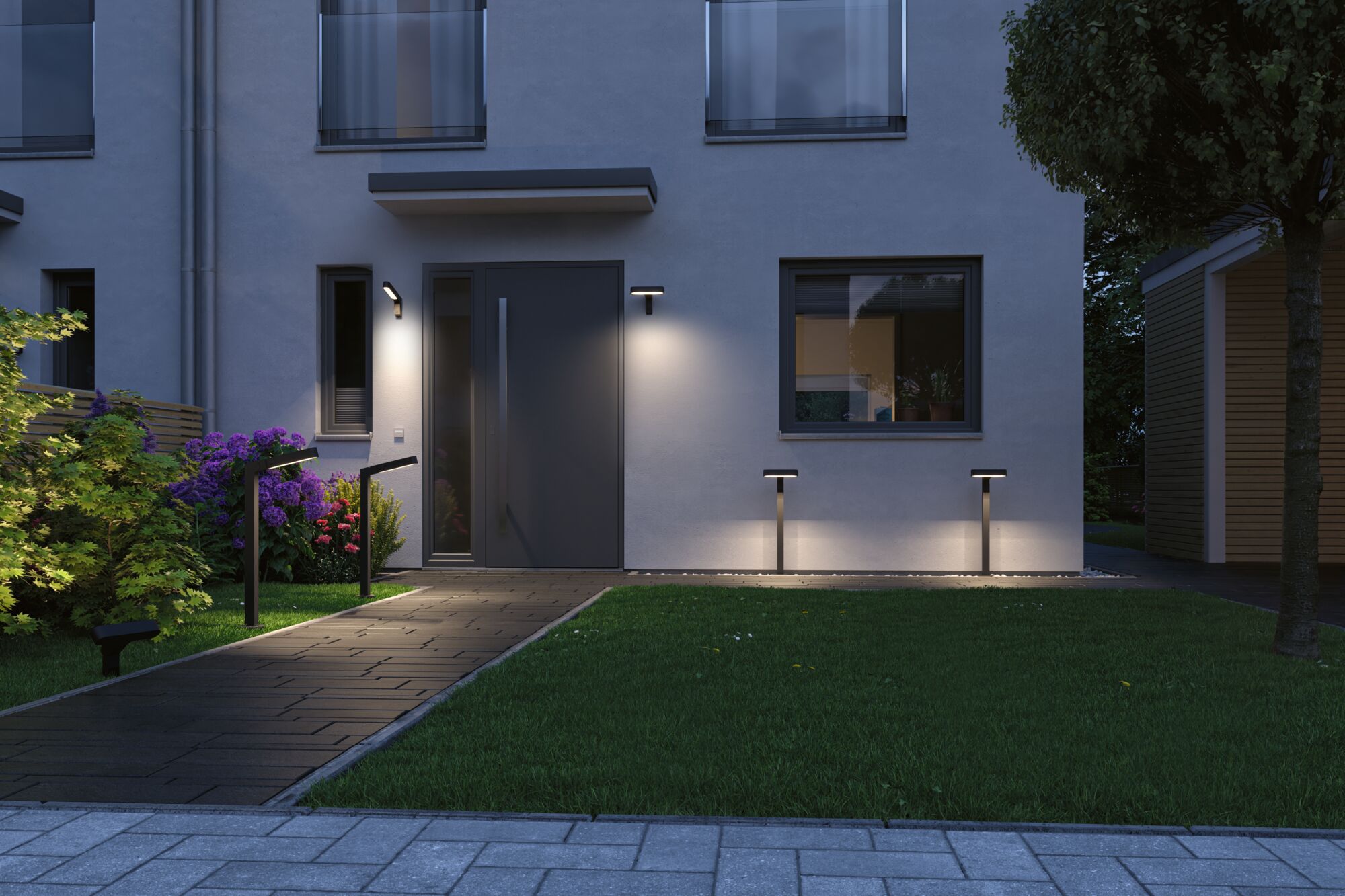 Modern black outdoor wall and bollard lights illuminate the entrance area with garden path at dusk.