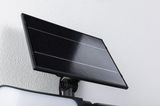 Schwarzes Solarpanel aus Glas und Aluminium an weißer Wand montiert für nachhaltige Beleuchtung