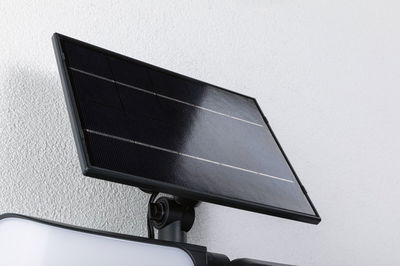 Schwarzes Solarpanel aus Glas und Aluminium an weißer Wand montiert für nachhaltige Beleuchtung