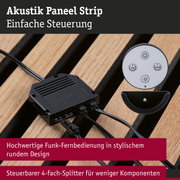 Akustik Paneel Strip mit schwarzem Kunststoff-Splitter und runder Funk-Fernbedienung auf Holzuntergrund