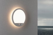 Round white plastic outdoor wall light with warm white LED and motion sensor by the sea