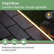 Bandeau LED blanc chaud entre dalles en pierre et gazon synthétique pour éclairage extérieur