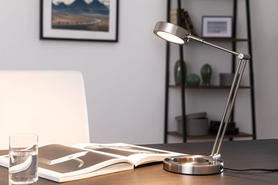 Moderne LED-Tischleuchte aus gebürstetem Edelstahl mit verstellbarem Arm auf Schreibtisch.