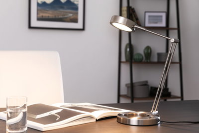 Moderne LED-Tischleuchte aus gebürstetem Edelstahl mit verstellbarem Arm auf Schreibtisch.