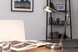 Moderne LED-Tischleuchte aus gebürstetem Edelstahl mit verstellbarem Arm auf Schreibtisch.