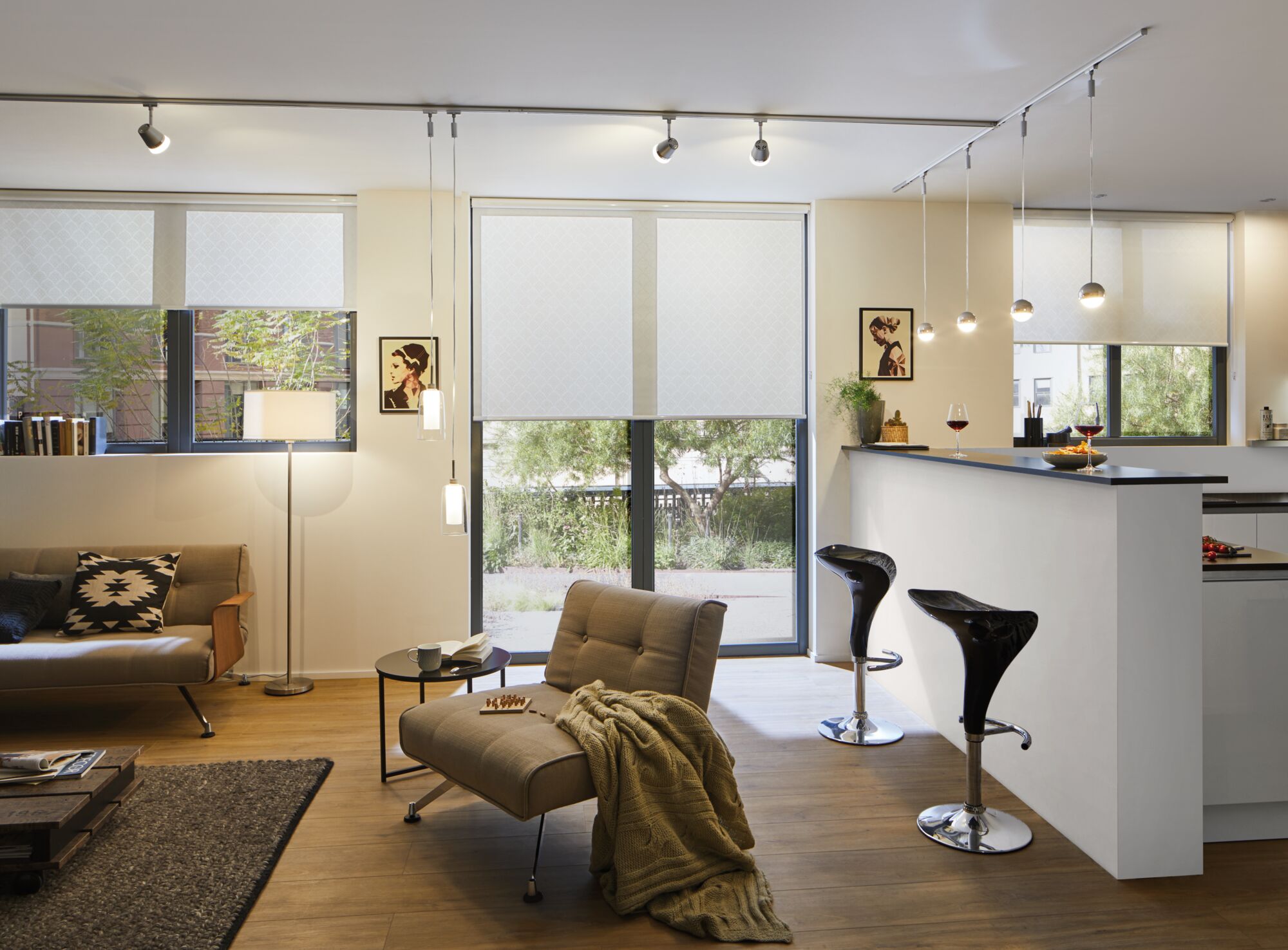 Salon moderne avec stores blancs, fauteuil beige, tabourets de bar noirs et sol en bois éclairé par des spots LED
