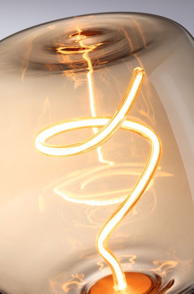Close-up of warm white LED bulb with curved filament inside amber-colored glass for ambient lighting