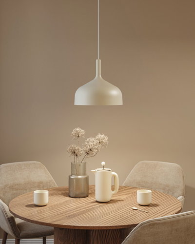 Beige metal pendant lamp above round wooden table with coffee pot and vase in dining room