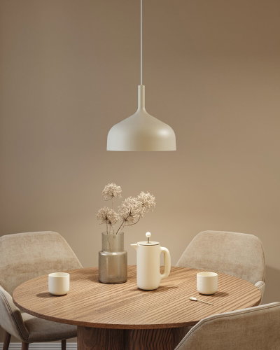 Beige metalen hanglamp boven ronde houten tafel met koffiepot en vaas in eetkamer