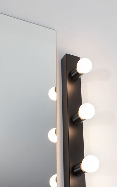 Black wall lamp with five round white LED bulbs beside mirror for bathroom lighting