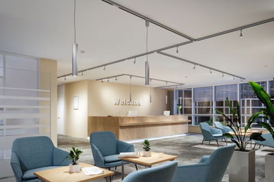 Modern reception area with wooden desk, blue armchairs and LED ceiling lights for office lighting