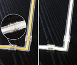 LED strip light with transparent corner connector on black surface, warm white light and close-up detail.