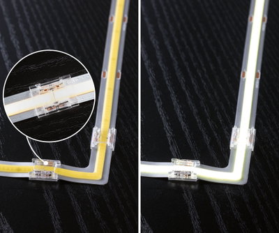 LED strip light with transparent corner connector on black surface, warm white light and close-up detail.