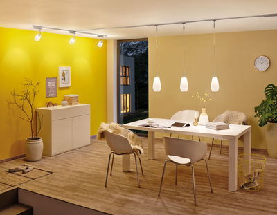 Moderne spisestue med hvide stole, trægulv, gule vægge, oplyst af LED-loftspots.