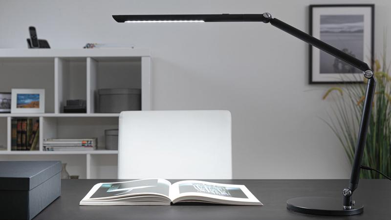 Zwarte LED-bureaulamp met verstelbare arm op moderne werkplek met open boek, kantoorverlichting.