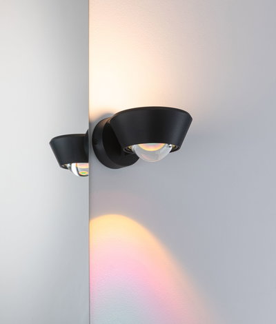 Black metal wall light with glass globe casting warm light for modern interior lighting