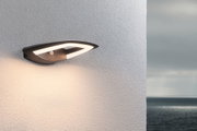 Moderne schwarze LED-Außenwandleuchte mit Bewegungsmelder an weißer Wand mit Meerblick