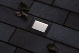 Rectangular black LED recessed floor light with warm white illumination on dark pavement.
