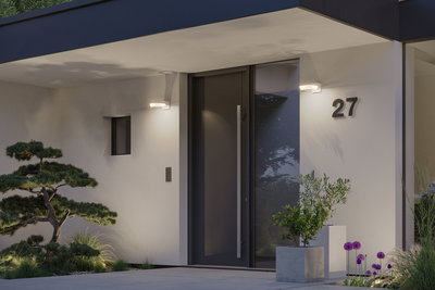 Moderne witte gevel met zwarte deur en twee ronde LED-wandlampen die de ingang verlichten