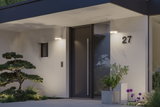 Modern white house facade with black door and two round LED wall lights illuminating the entrance