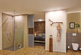 Modern bathroom with open shower, wooden floor, and natural decor highlighting stylish room lighting