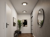 Modern hallway with round wall mirror and two black and white ceiling lights, wooden floor