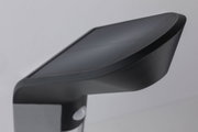 Schwarze Kunststoff-Außenleuchte mit modernem Design und Bewegungsmelder für Gartenbeleuchtung.