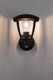 Schwarze Außenwandleuchte aus Metall mit klarem Glas und sichtbarer LED-Glühbirne an grauer Wand