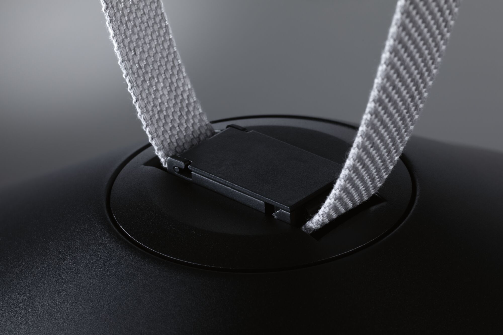 Close-up of black plastic clip with grey fabric strap for lighting accessory.