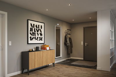 Moderner Flur mit Holzsideboard, grauer Wand und schwarzen Einbaustrahlern für stilvolle Beleuchtung