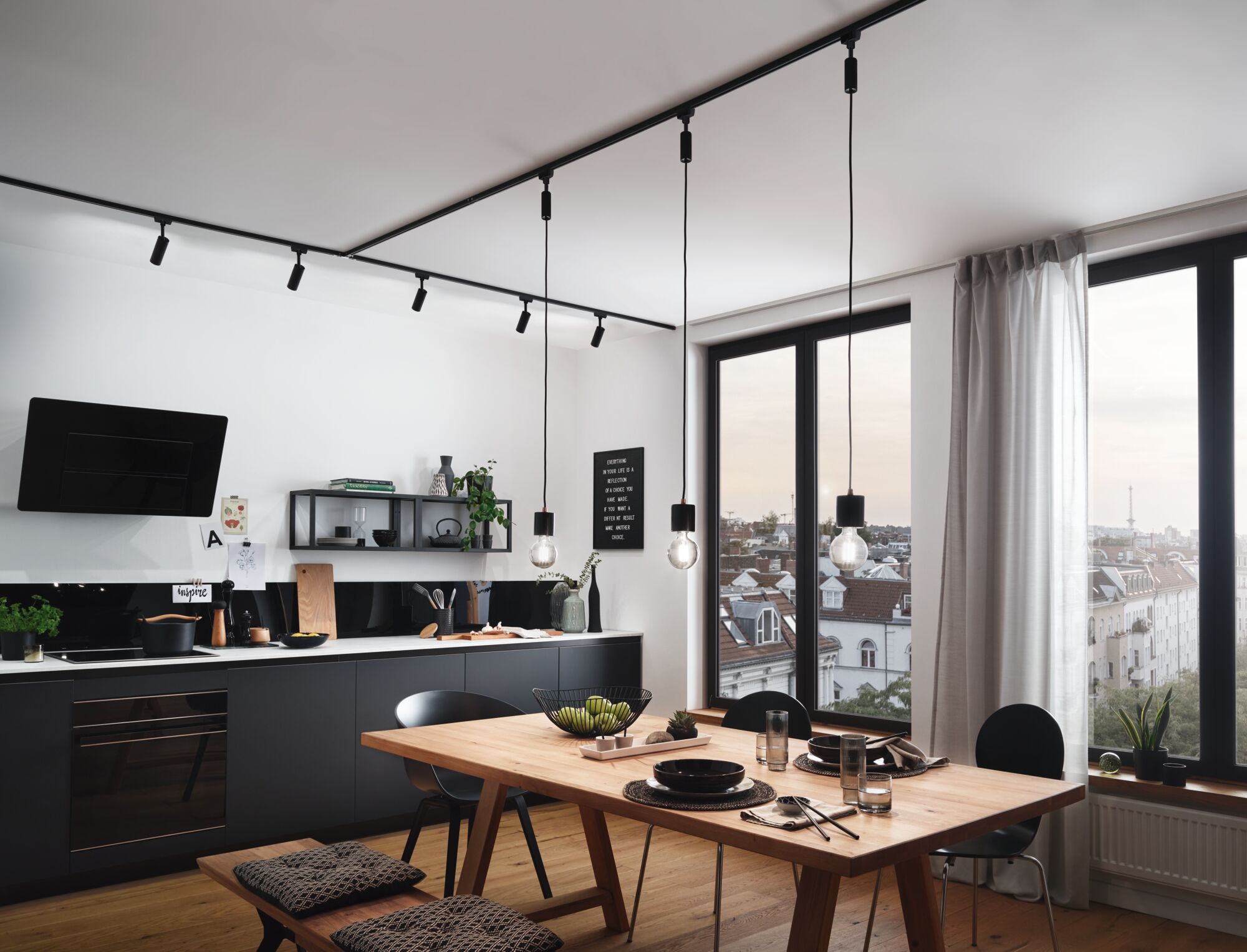 Moderne keuken met zwarte rails en hanglampen, houten eettafel en stadszicht bij daglicht