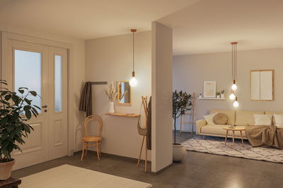 Moderne woonkamer met beige bank, vloerkleed en hangende koperen LED-lampen voor warme verlichting.