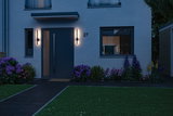 Modern house with dark blue door and two slim black outdoor wall lights at dusk