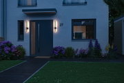 Modern house with dark blue door and two slim black outdoor wall lights at dusk